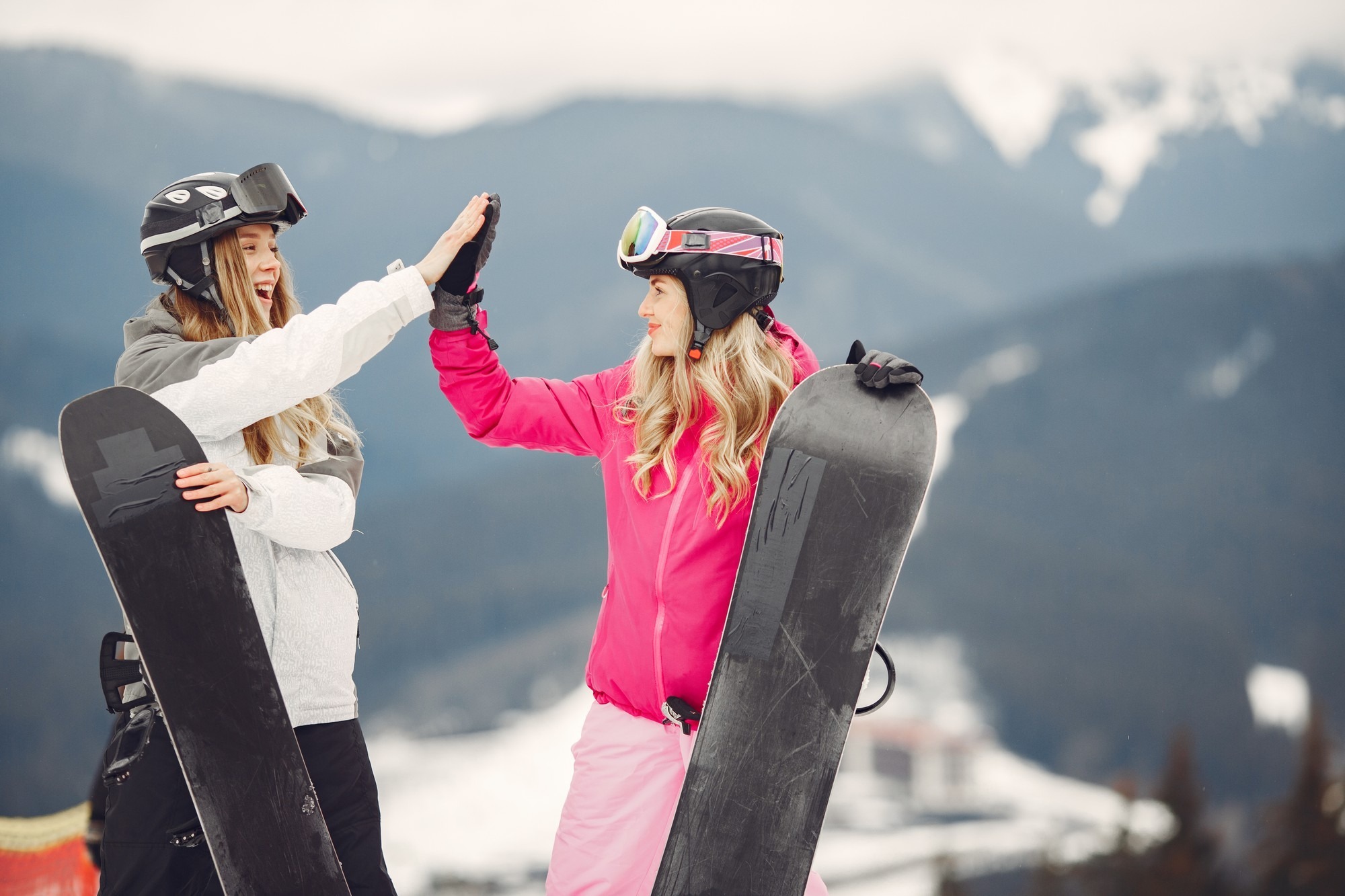 donne-in-tuta-da-snowboard-sportive-su-una-montagna-con-uno-snowboard-in-mano-all-orizzonte-concetto-di-sport